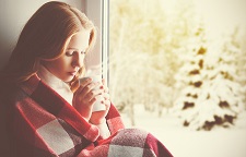 46636841 - pensive sad girl with a warming drink looking out the window in the winter forest