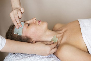 84917142 - young woman have face guasha treatment at asian beauty clinic